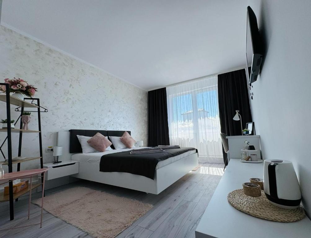 a white bedroom with a bed and a tv at Sara room in Curtea de Argeş