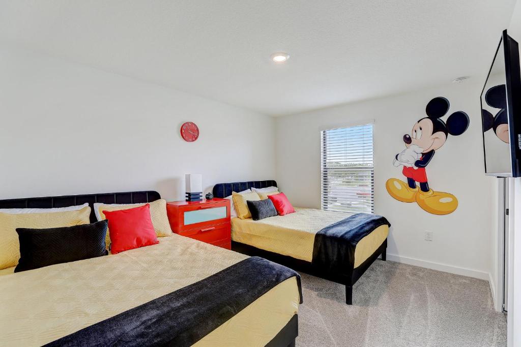 a bedroom with two beds and a mickey mouse on the wall at Kissimmee Modern 3BR Home With a pool & Close to Beach in Kissimmee
