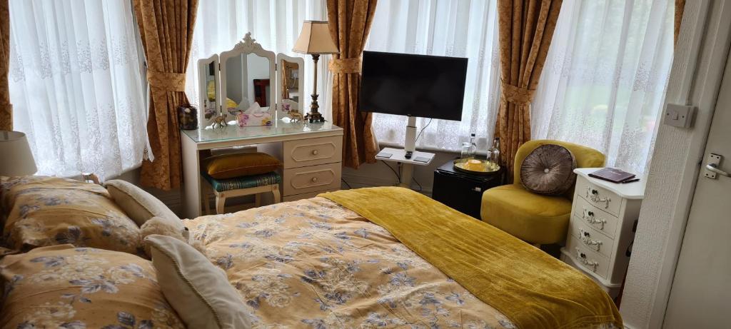 a bedroom with a bed and a television and a chair at The Chantry hotel in Dronfield