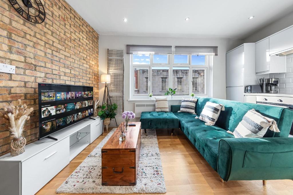uma sala de estar com um sofá verde e uma parede de tijolos em Boho 1-BR Peakham Rye Lane em Londres