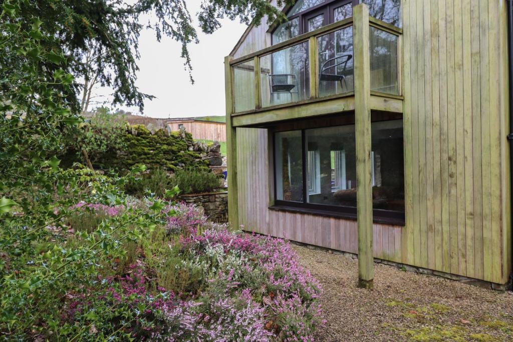 une maison en bois avec une fenêtre dans un jardin dans l'établissement The Gardener's Bothy, à Penrith