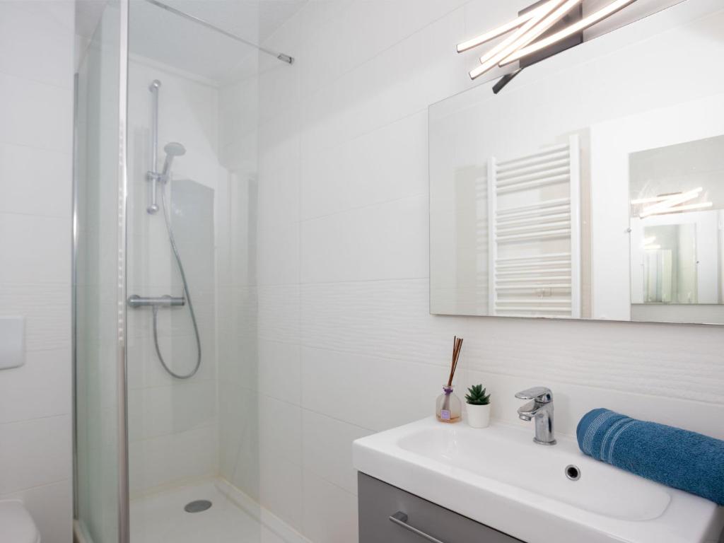 a white bathroom with a sink and a shower at Studio East Land-3 by Interhome in La Grande Motte