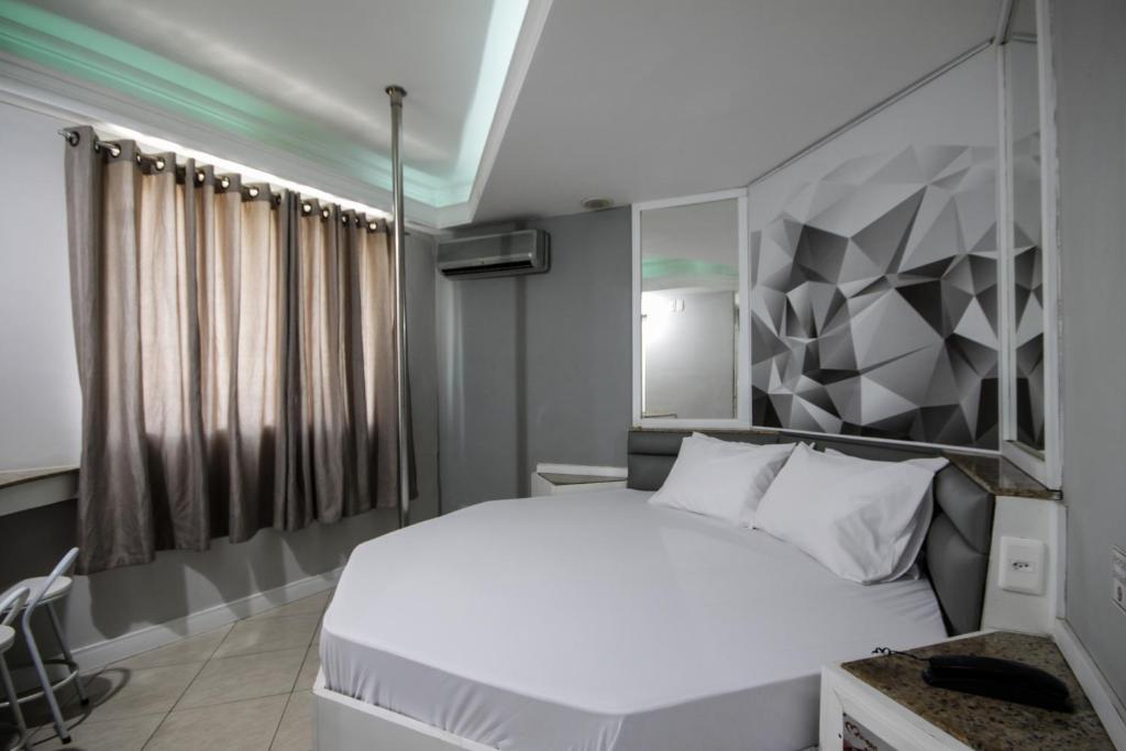 a bedroom with a white bed with a geometric wall at Mirage Motel Guarulhos in Sao Paulo