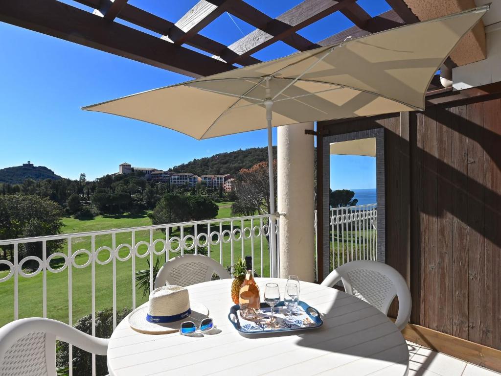 - une table blanche avec un parasol sur le balcon dans l'établissement Apartment L'Esquinade - F4 218 by Interhome, à Agay