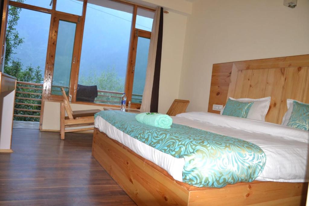 een slaapkamer met een bed en een balkon met ramen bij hotel sparkling in Manāli