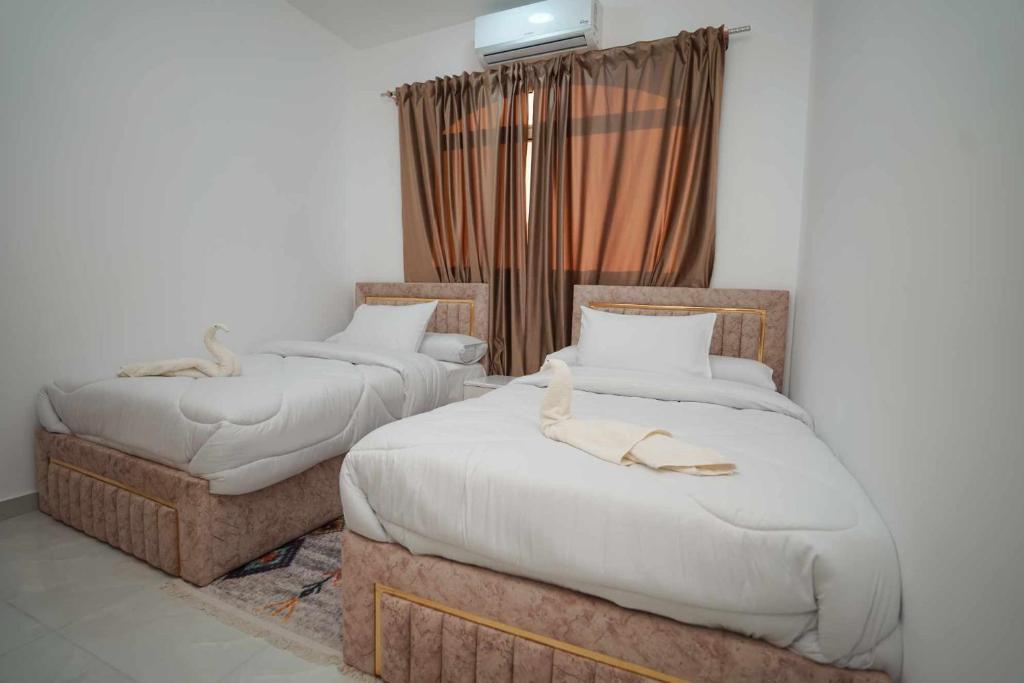 two twin beds in a room with a window at Hostel in Quseir