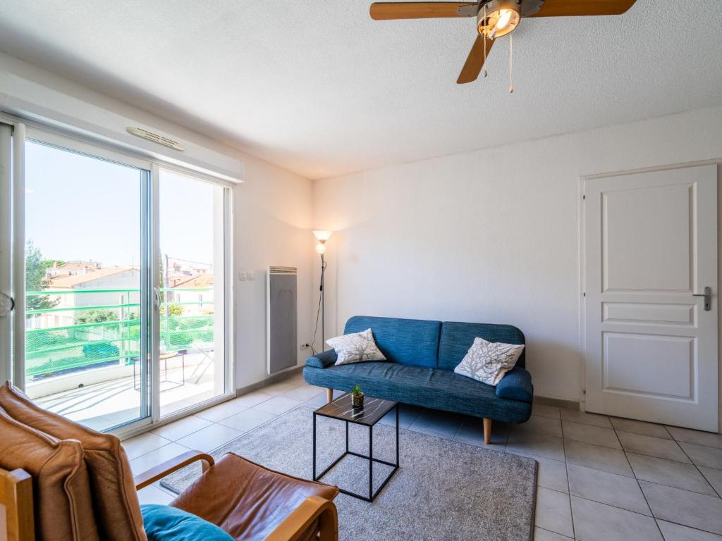 un salon avec un canapé bleu et une grande fenêtre dans l'établissement Apartment Les Capucines by Interhome, à Narbonne
