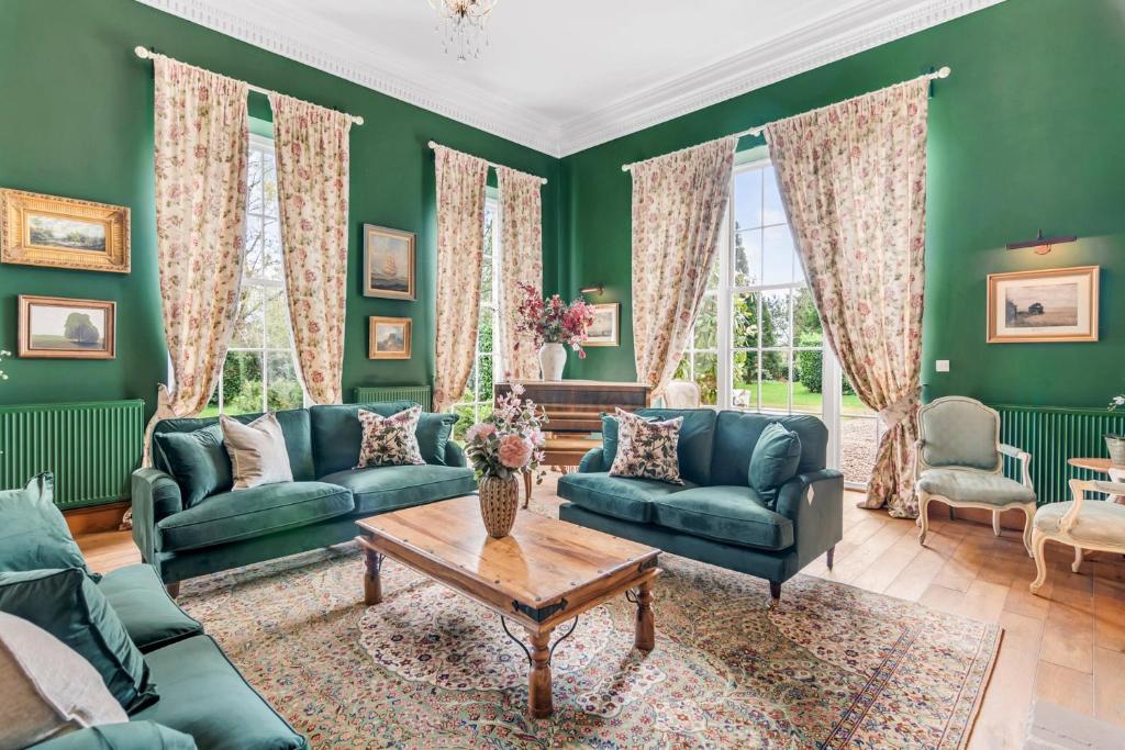 a living room with green walls and couches and a table at Beccles Georgian Mansion l 9 Bedrooms, Hot Tub & Parkland in Beccles