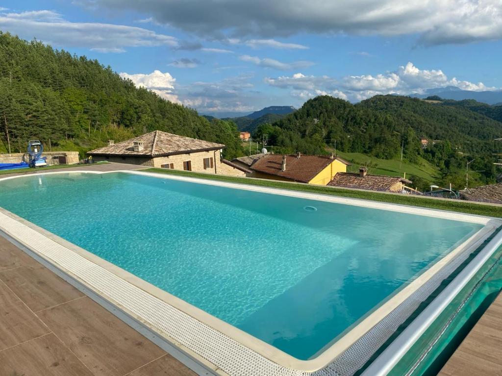 a large swimming pool with mountains in the background at Ca' Nobili - Charming Country House 