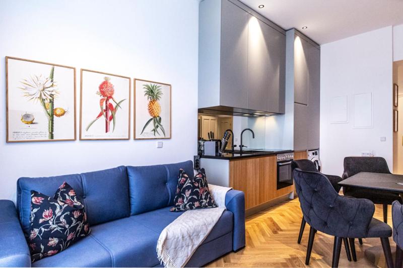 a living room with a blue couch and a kitchen at sgrafit apartments in Retz