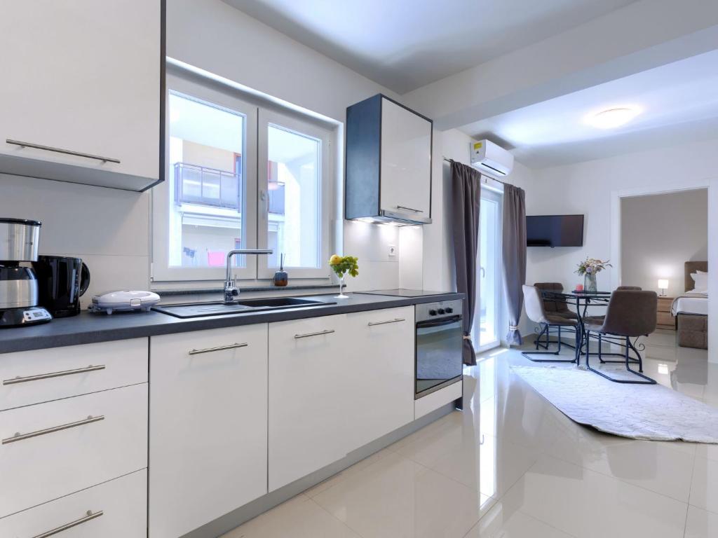 cocina con armarios blancos y sala de estar. en Apartment Villa Amra-5 by Interhome, en Poreč