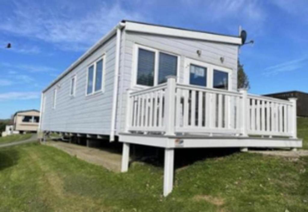 a tiny house is sitting on the grass at Inviting 2-Bed Caravan on Combe Haven Holiday Park in Hollington