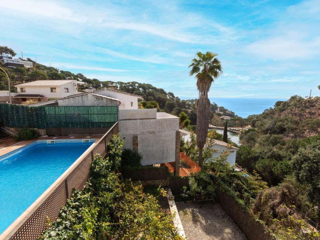 a villa with a swimming pool and a palm tree at Holiday Home Escorpio-1 by Interhome in Tossa de Mar