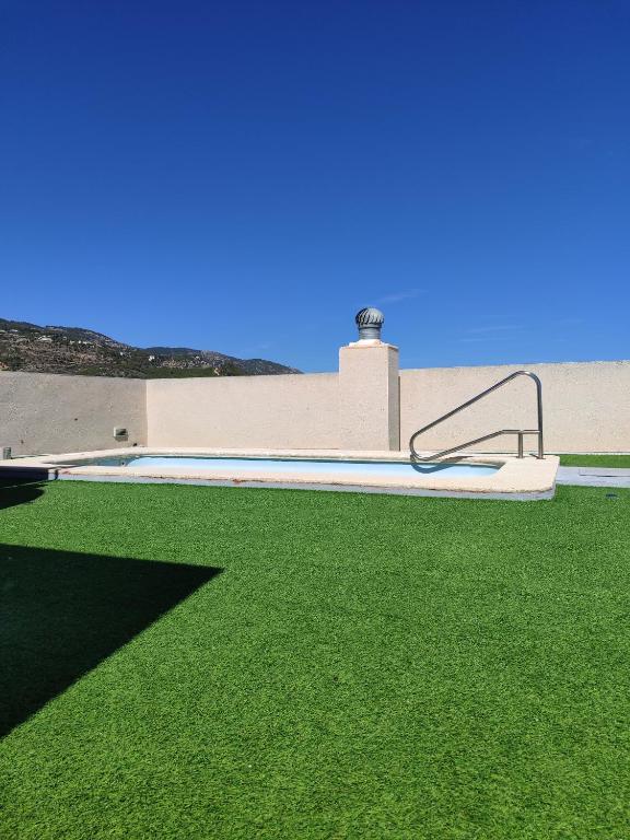 a swimming pool with green grass next to a building at Kione Vidalmar in Alcossebre