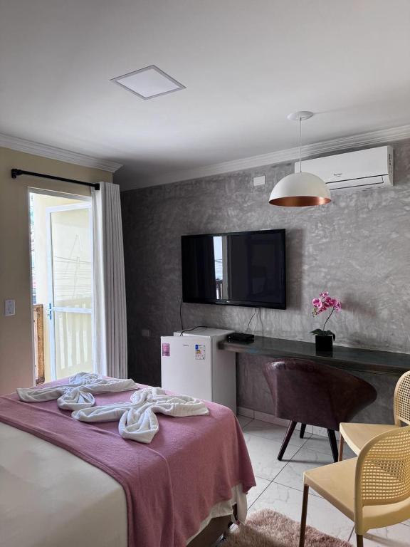 a bedroom with a bed and a desk and a television at Fabika Pousada in Maragogi