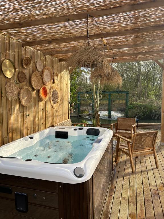 bañera de hidromasaje en una terraza de madera en Magnifique chalet en bord de rivière, en Saint-Avit-les-Guespières