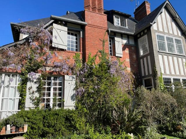 a large red brick house with white windows and bushes at Chambres d'Hôtes & SPA Le Chat Chez Qui j'Habite in Saint-Aubin-sur-Mer