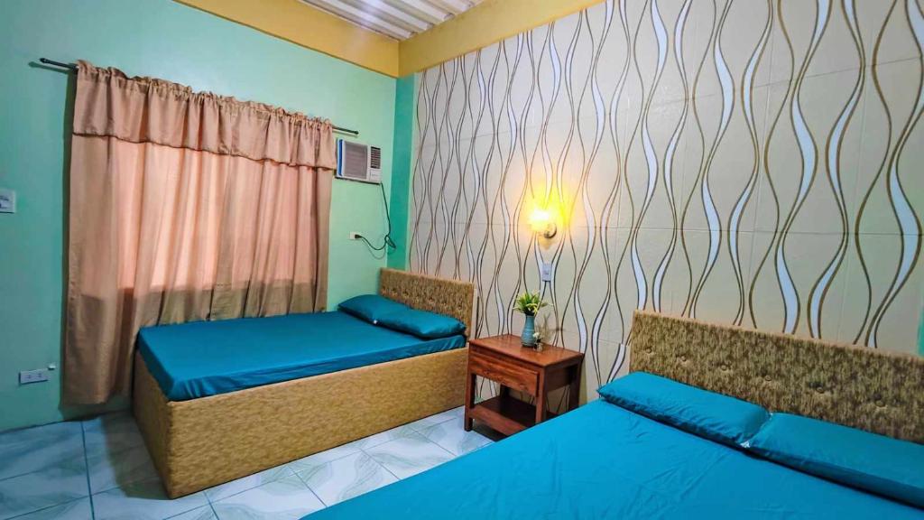 a bedroom with two beds and a table with a lamp at Emshienell Beach Resort and Event Place in Zambales