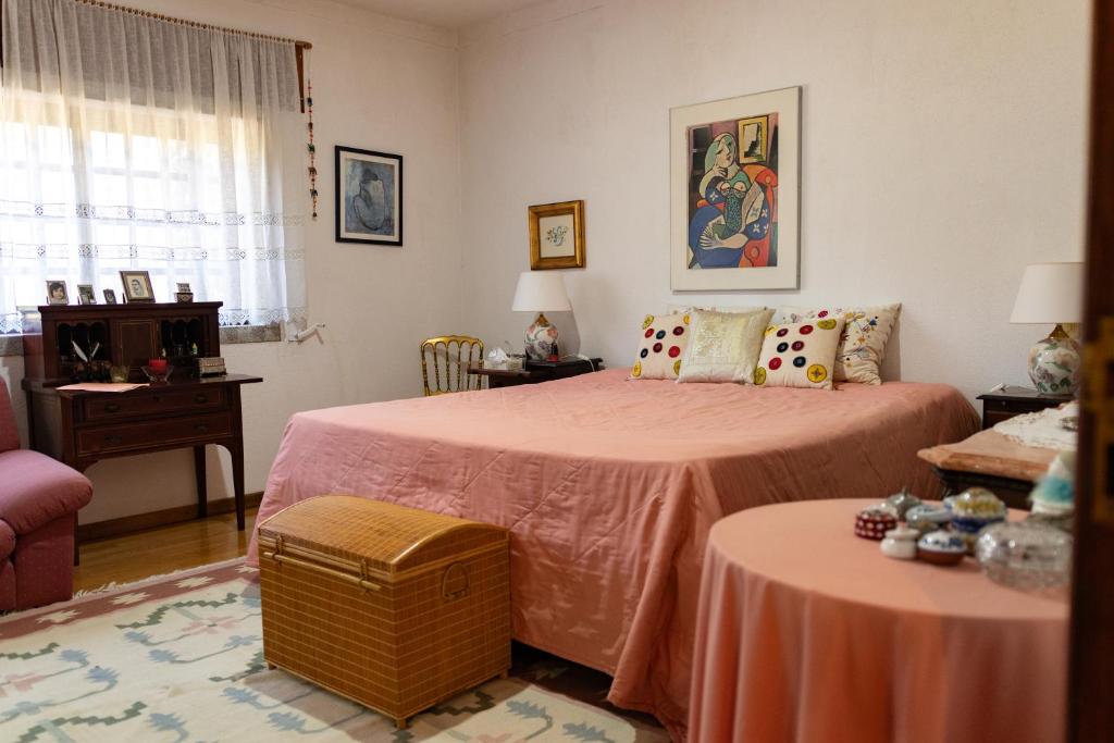 a bedroom with two beds with pink sheets and a table at Quinta dos Sinçais in Guarda