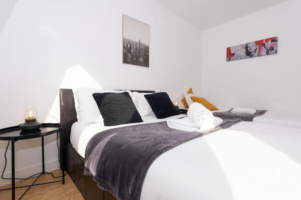 a bedroom with two beds and a side table at Shoreditch Apartments by DC London Rooms in London