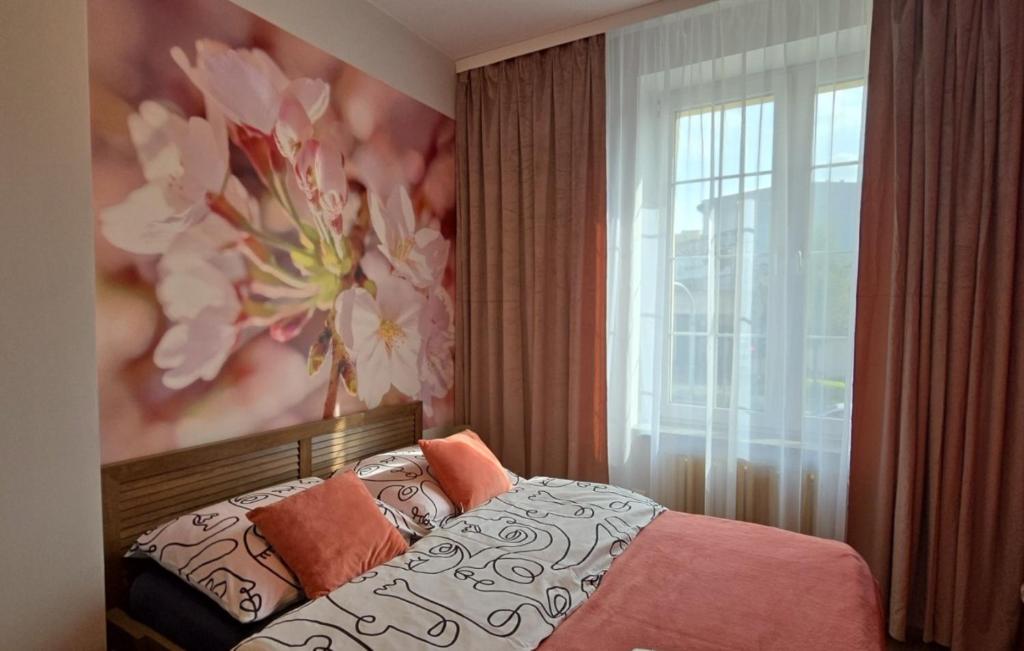 a bedroom with a bed with a flower painting on the wall at Apartament Pod 12 in Bielsko-Biała