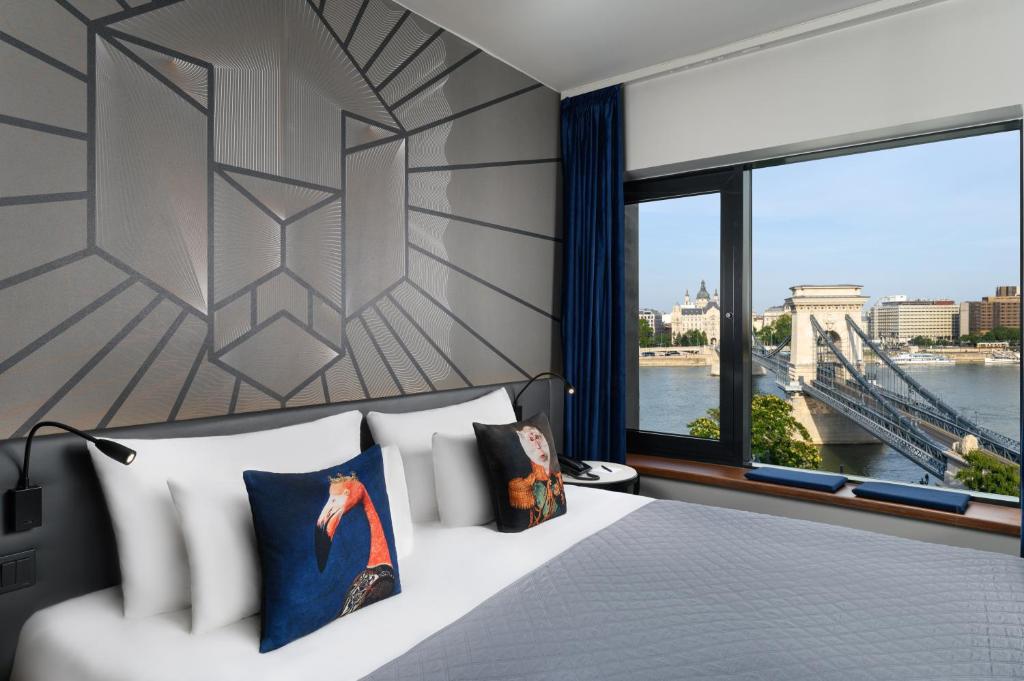 a bedroom with a bed and a window with a bridge at Hotel Clark Budapest - Adults Only in Budapest