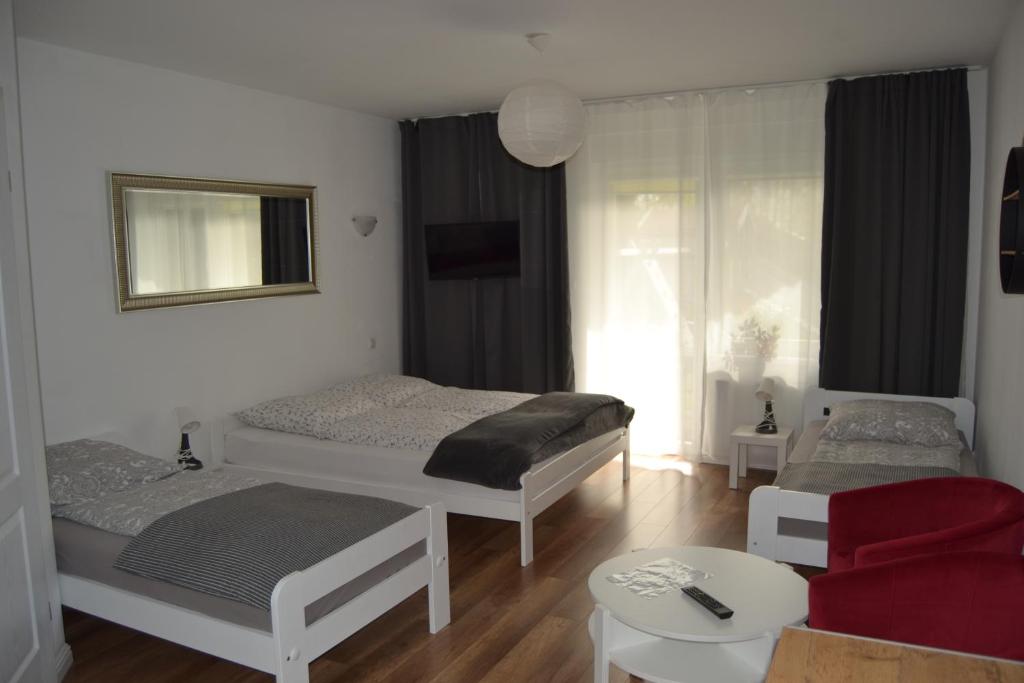 1 dormitorio con 2 camas y silla roja en Dom Goscinny Aurora, en Dziwnówek