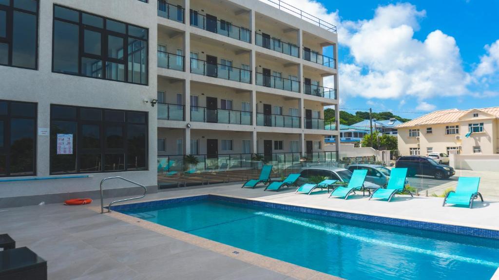a swimming pool with blue chairs next to a building at LUXE MORDERN RESIDENTIAL LIVING INC. in Lance aux Épines