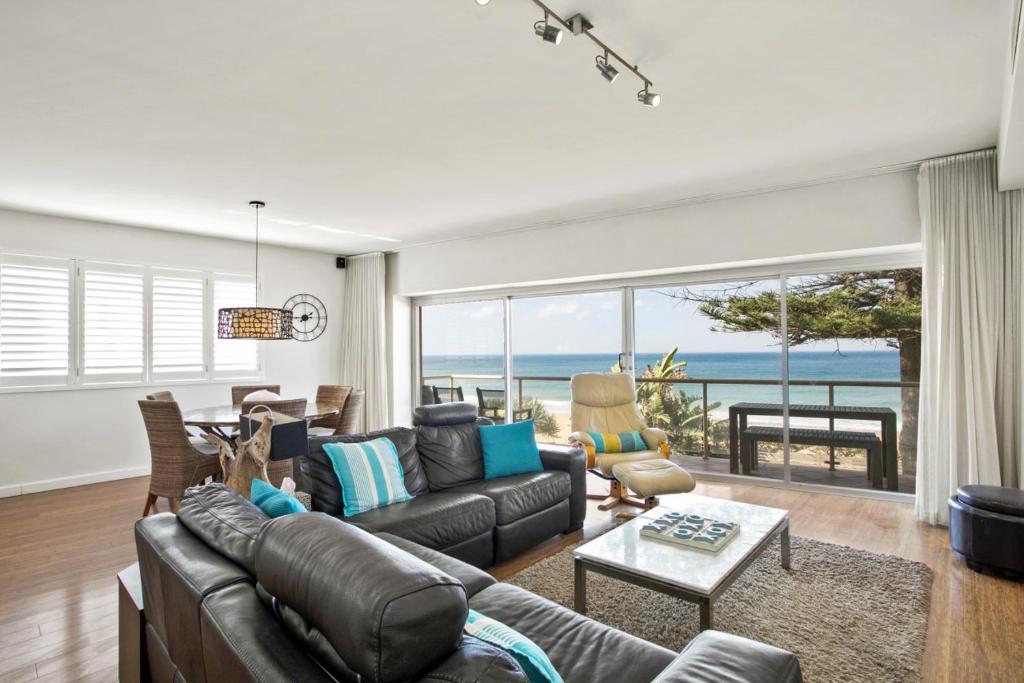 a living room with a couch and a view of the ocean at Beachfront Dream - Direct Beachfront in Narrabeen