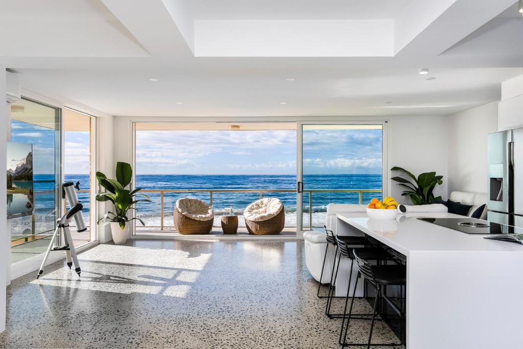 a white kitchen with a view of the ocean at Yulunga - Direct Beachfront in Narrabeen