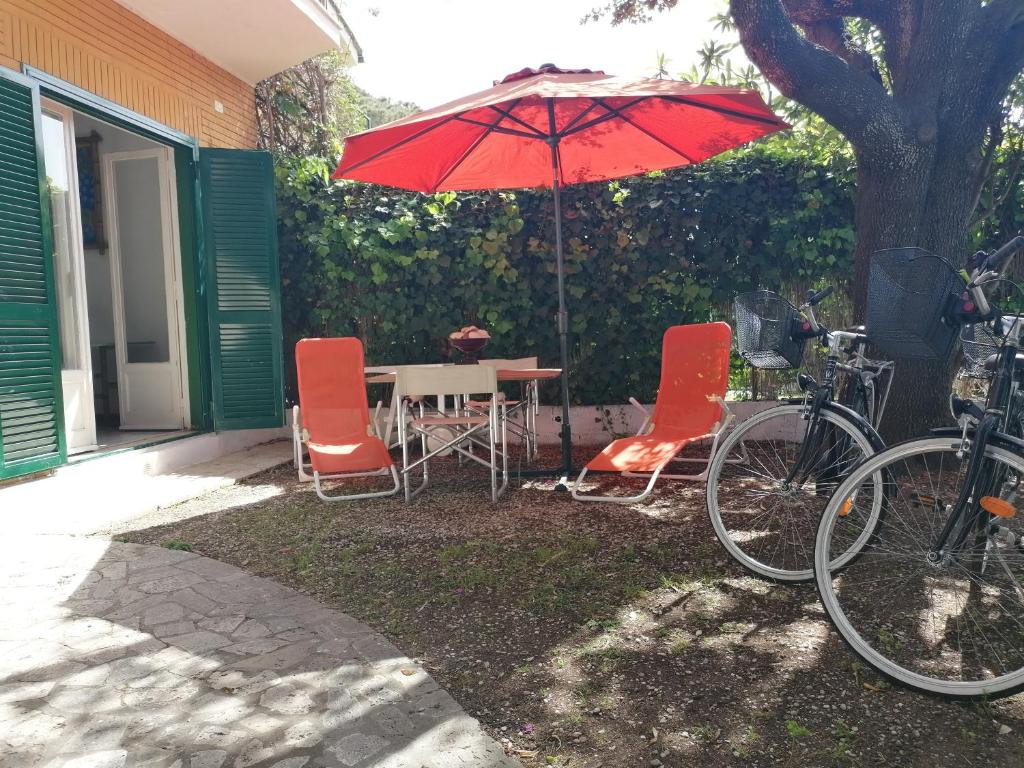 einen Tisch und Stühle mit einem Regenschirm neben einem Haus in der Unterkunft Vacanze degli Sposi in Fregene