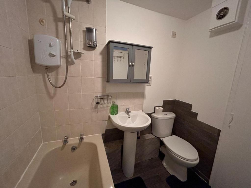 Specious 1 Bed Apartment free wifi and parking في Goodmayes: حمام مع حوض ومرحاض وحوض استحمام