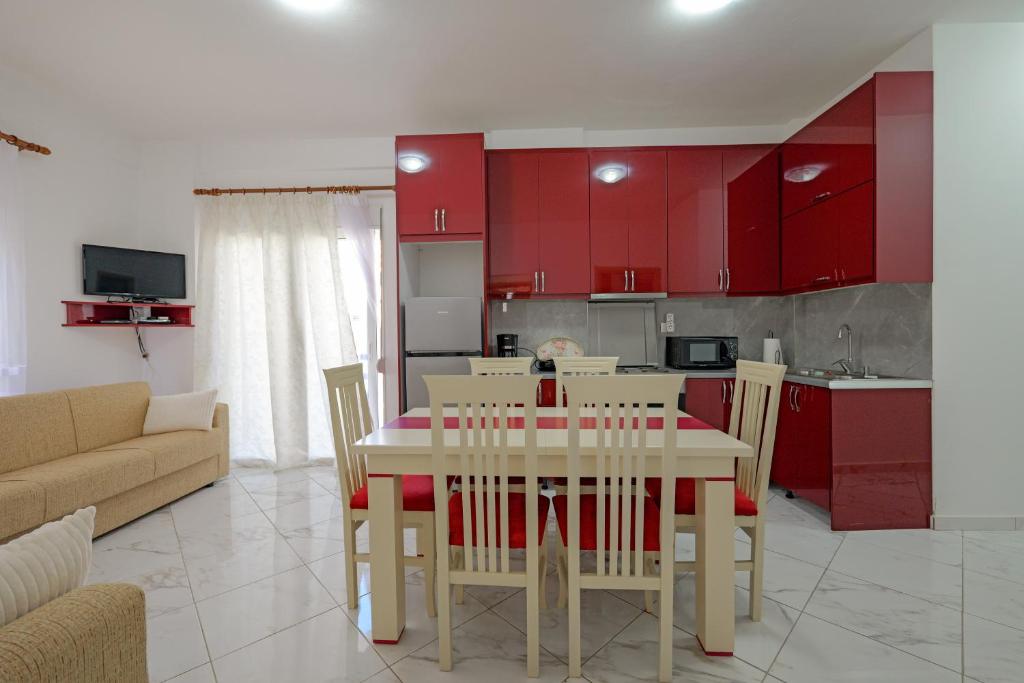 a kitchen and dining room with red cabinets and a table and chairs at Valentina Apartment 1 in Sarandë