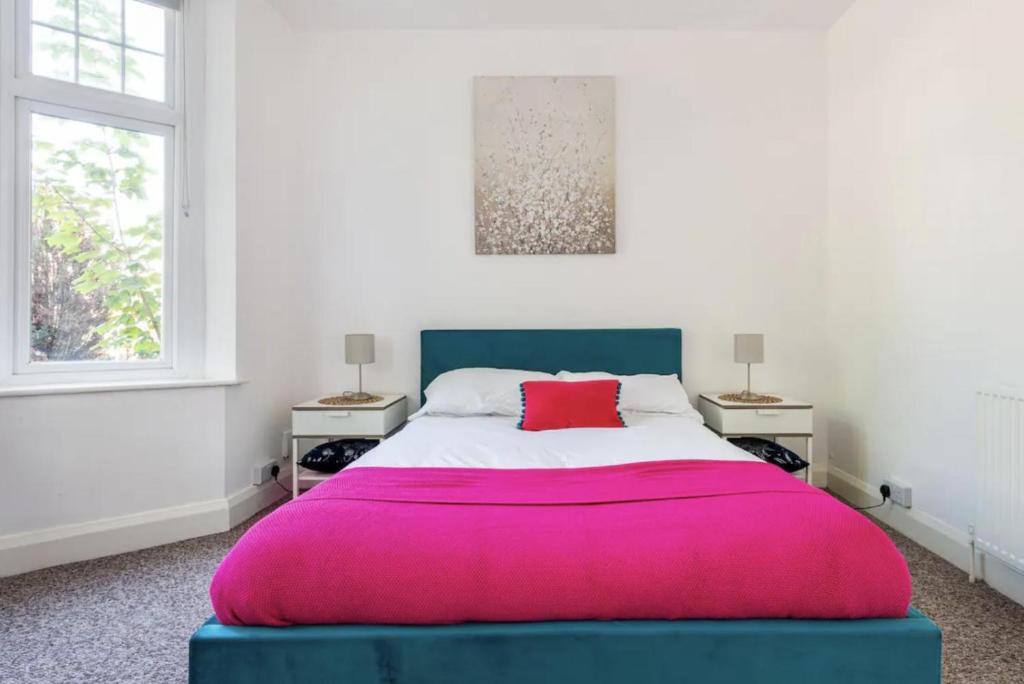 een slaapkamer met een groot roze bed en 2 ramen bij Beautiful 1-Bed Apartment with Garden in London in Londen