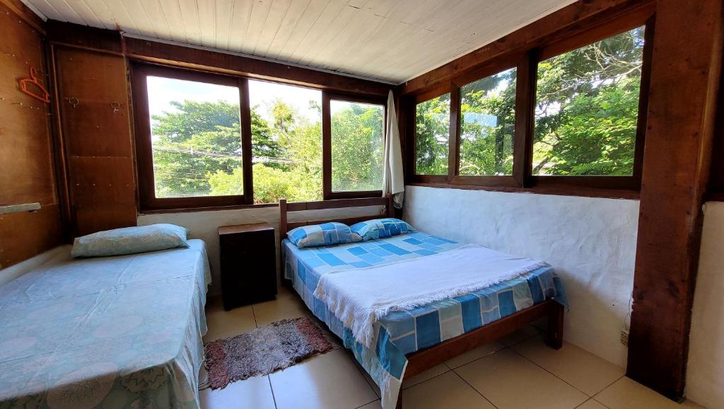 een slaapkamer met 2 bedden in een kamer met ramen bij Pousada Ancore in São Sebastião