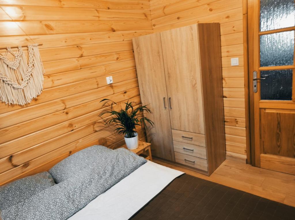 1 dormitorio con 1 cama y pared de madera en Domek pod sosnami en Grodziczno