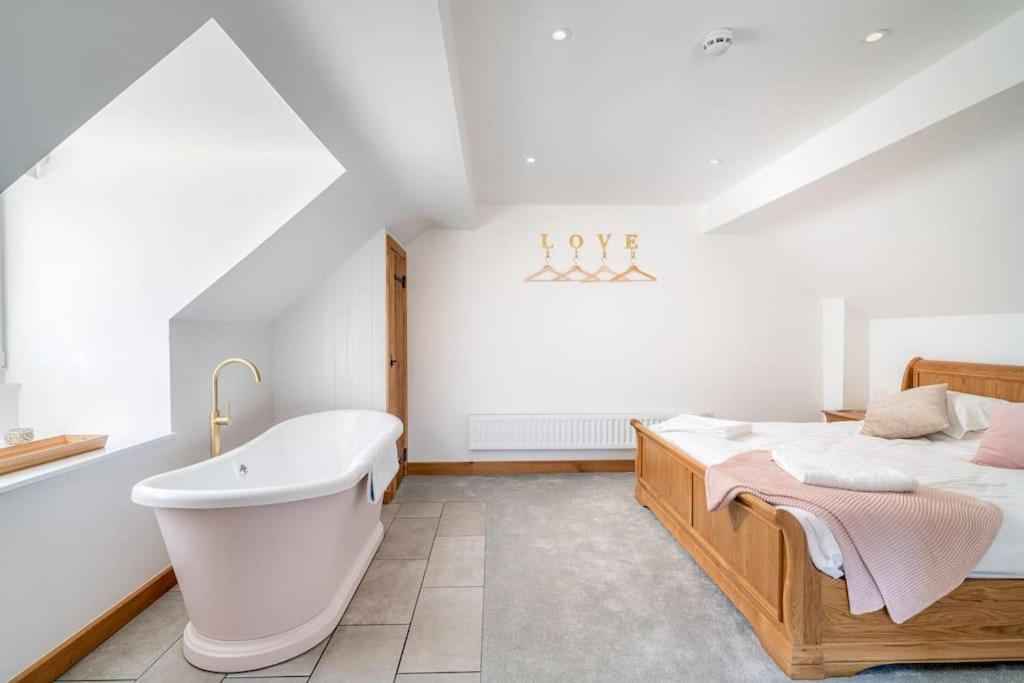 uma casa de banho com uma cama e uma banheira ao lado de uma cama sidx sidx em Old Dairy Cottage - Cosy and Luxurious! em Buckinghamshire
