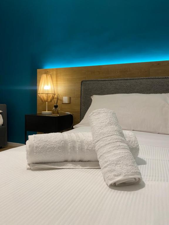 Una cama con toallas blancas y una pared azul. en Dimora Del Ragno, en Tívoli