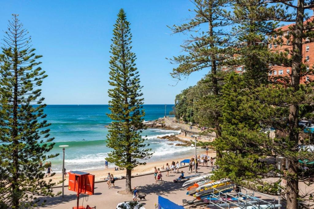 a beach with people and trees and the ocean at Dungawon - Beachfront in Sydney
