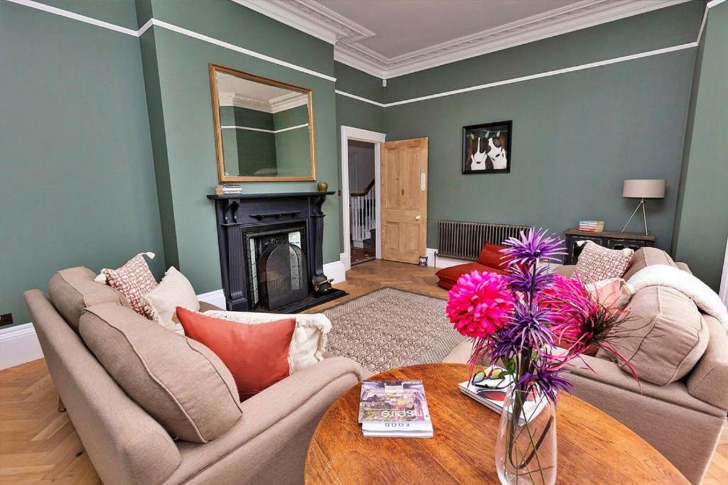 ein Wohnzimmer mit 2 Sofas und einem Tisch mit Blumen in der Unterkunft Finest Retreats - Portland House in Exmouth