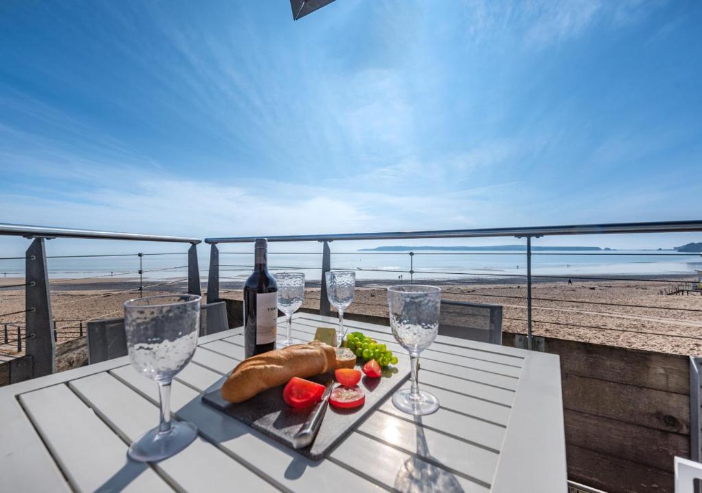 einen Tisch mit Weingläsern und einen Teller Essen am Strand in der Unterkunft Ty Traeth in Tenby