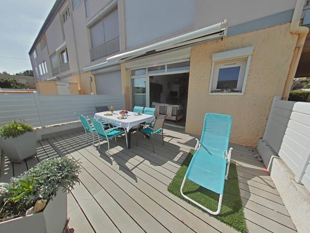 un patio avec une table et des chaises sur une terrasse dans l'établissement Vos vacances les pieds dans le sable., à Saint Pierre La Mer