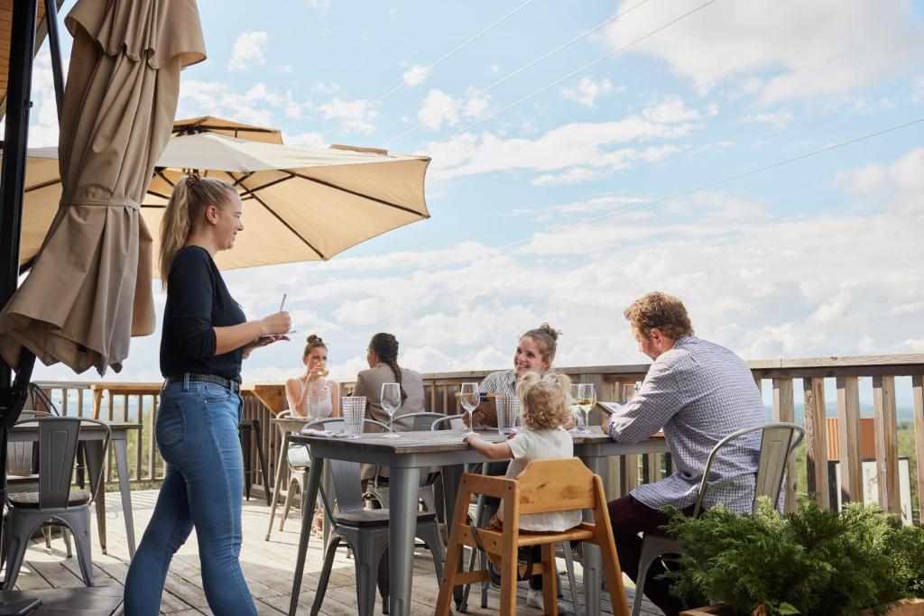 un groupe de personnes assises à une table sur un patio dans l'établissement Hotel de l'Horizon, à Sutton