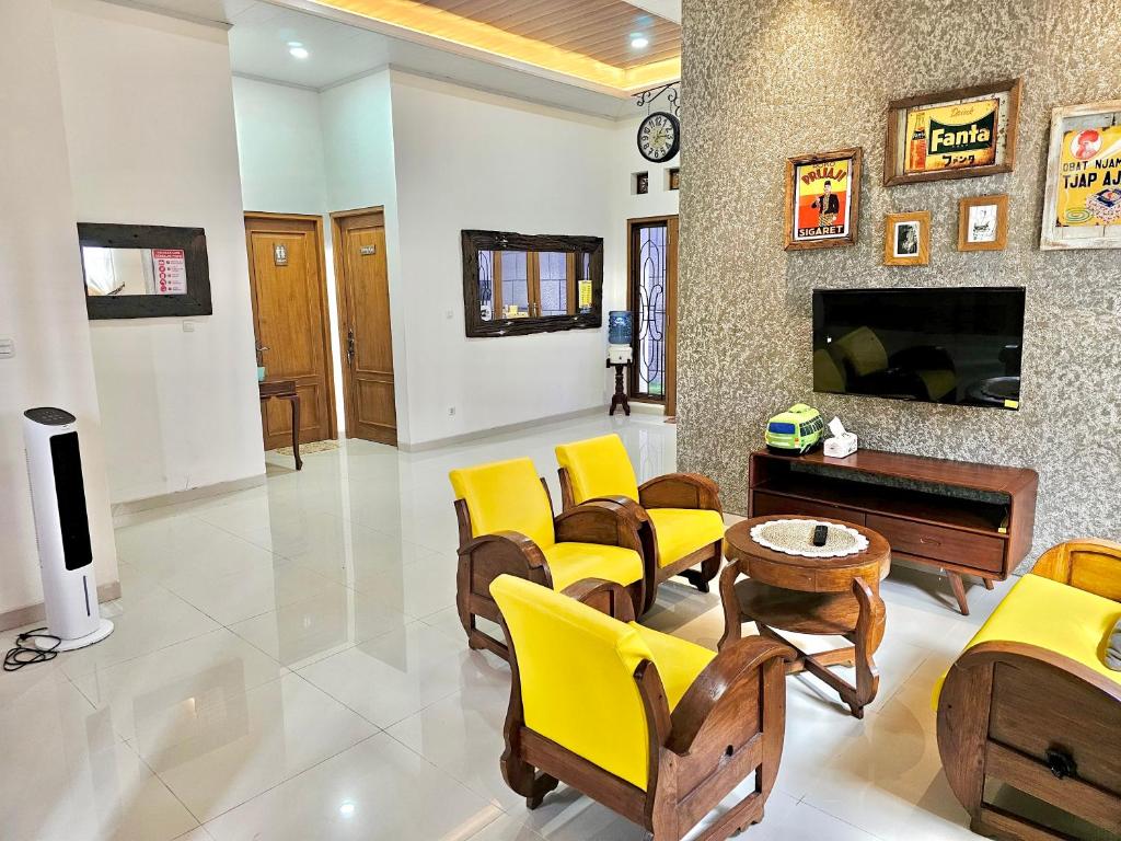 a living room with yellow chairs and a fireplace at Omah Tabon Jogja - Dekat Dengan Malioboro in Timuran