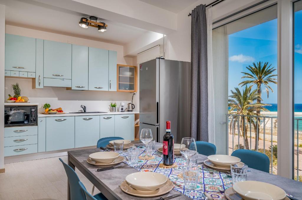 een keuken en eetkamer met een tafel met wijnglazen bij Appartamento Mare Blu a pochi passi dal mare in Balestrate
