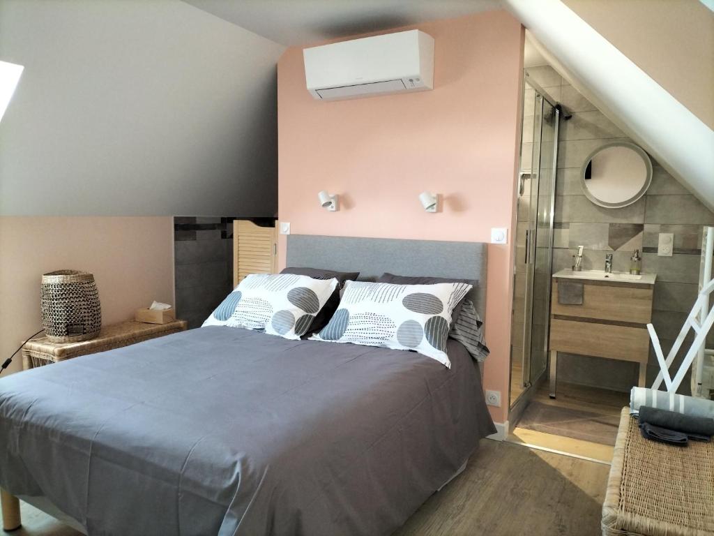 een slaapkamer met een bed en een badkamer met een wastafel bij Étape au Chemin des Dames - Chambre et table d'hôtes in Pontavert