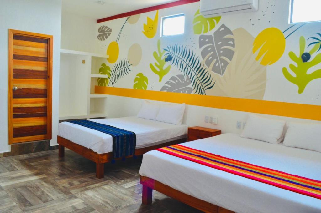 Habitación con 2 camas y un mural en la pared. en Hotel Axolotl en Puerto Escondido