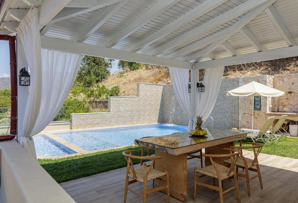 un patio con tavolo, sedie e piscina di Kampos Villa III, pure elegance, By ThinkVilla ad Akhladhés