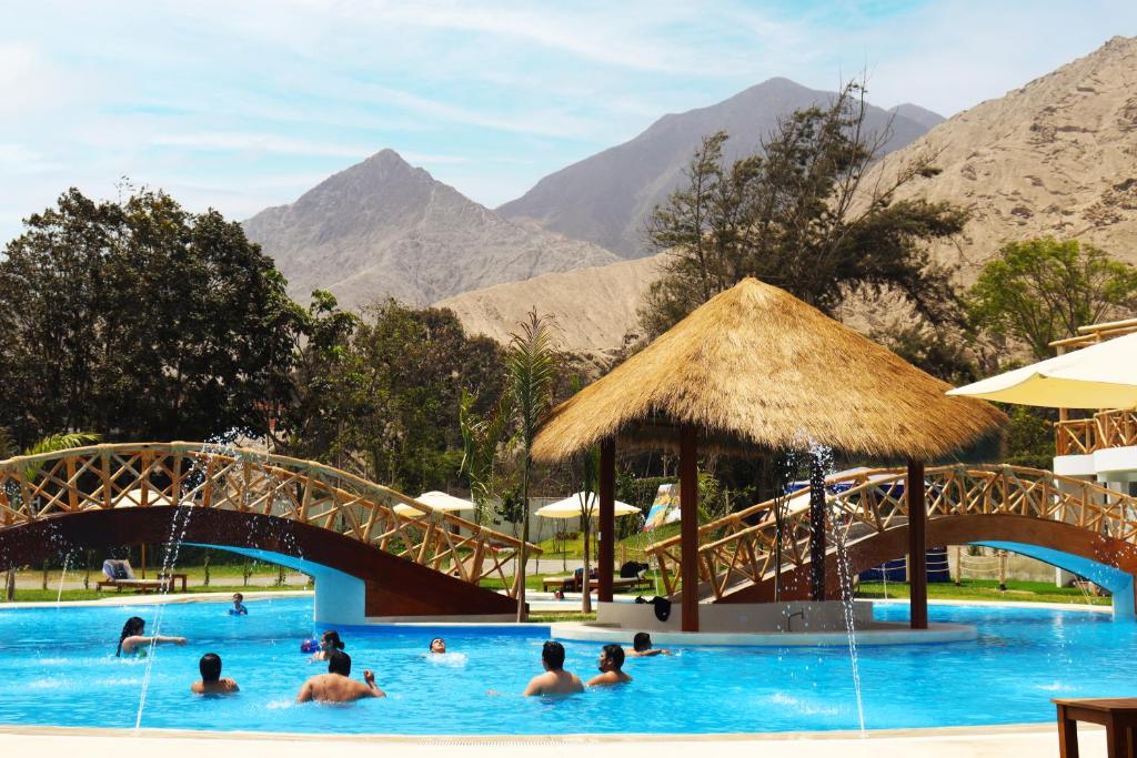 a group of people in a swimming pool with a bridge at Los Andes - Restaurant & Bungalows in Cieneguilla