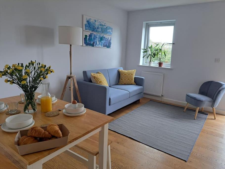 sala de estar con sofá azul y mesa en Vibrant Coastal Village Retreat- private parking en Lympstone